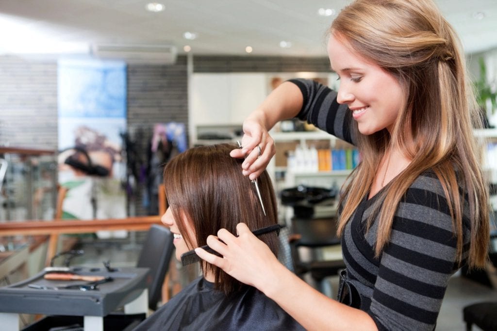 A Lady cutting another girls' hair in salon