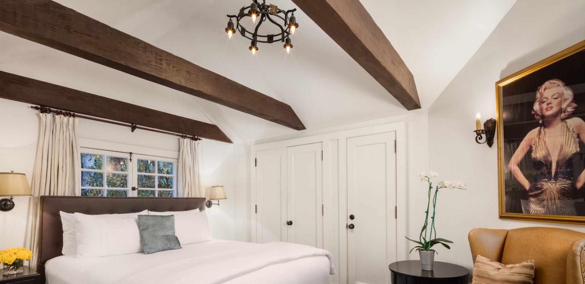 The Charlie Hotel is a bedroom with wooden beams and a painting on the wall.