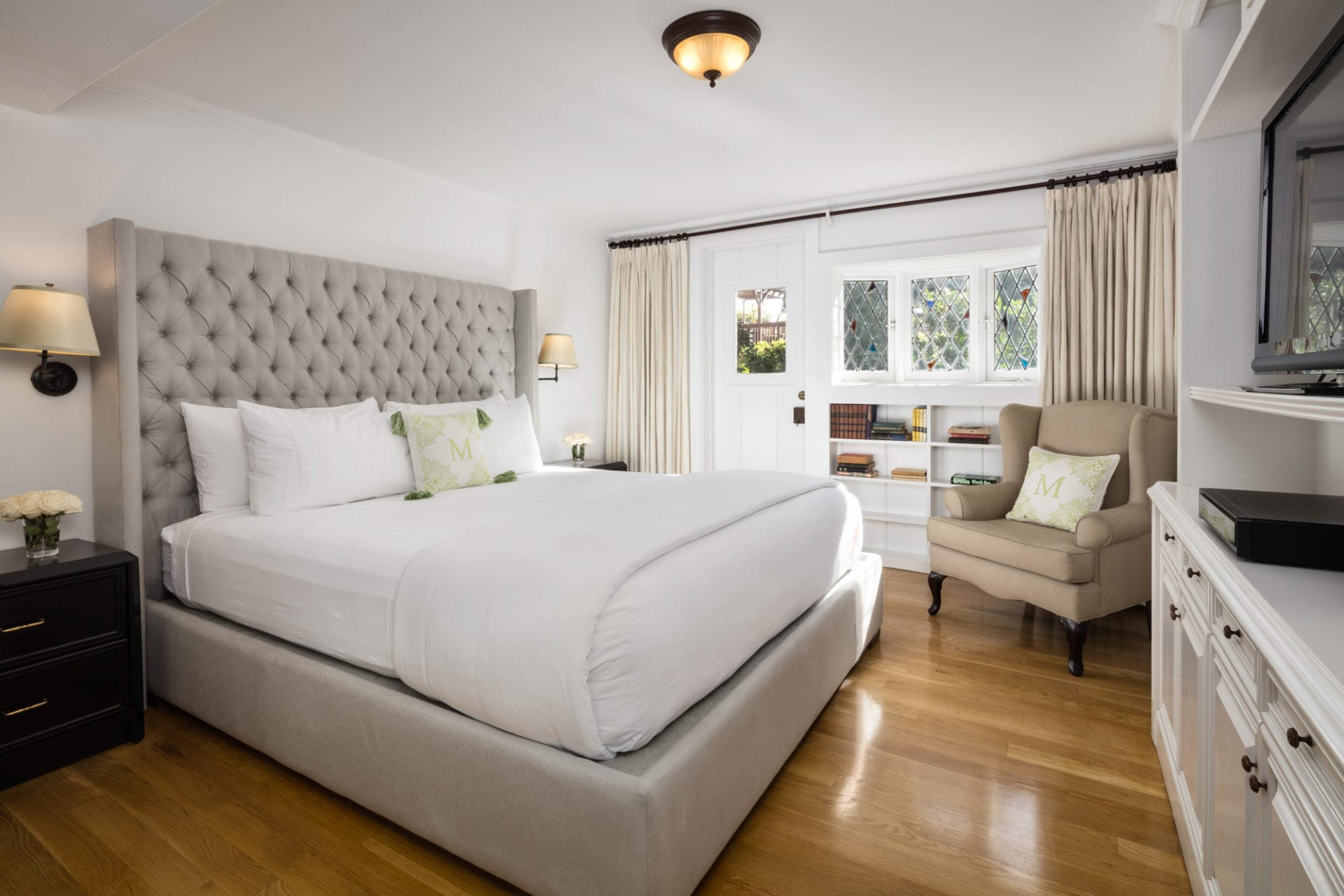 A bedroom at The Charlie Hotel with a white bed and wooden floors.