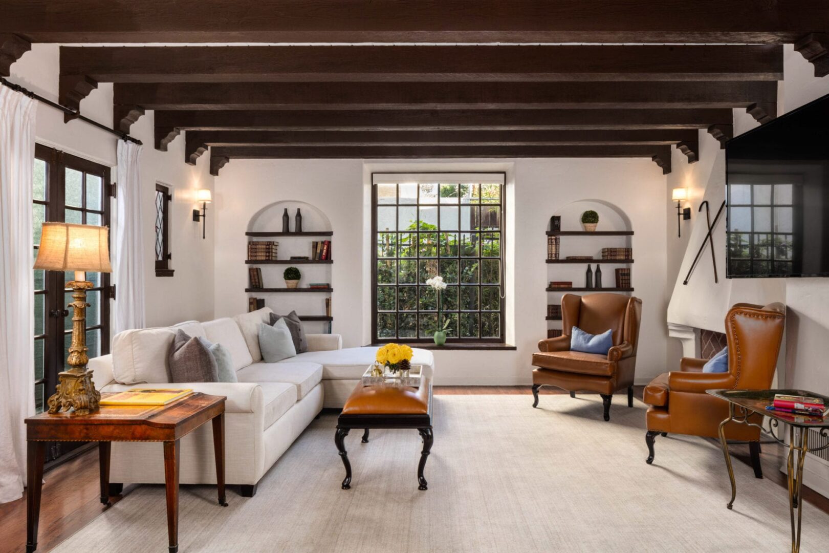 A living room with wood beams and white furniture.