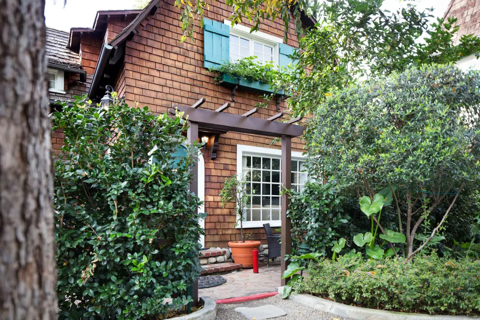 A small house with green shutters and potted plants.