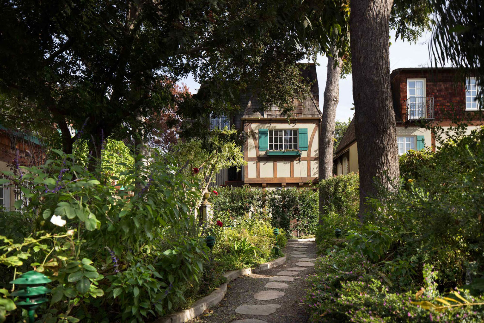 A pathway leads to a house in a garden.